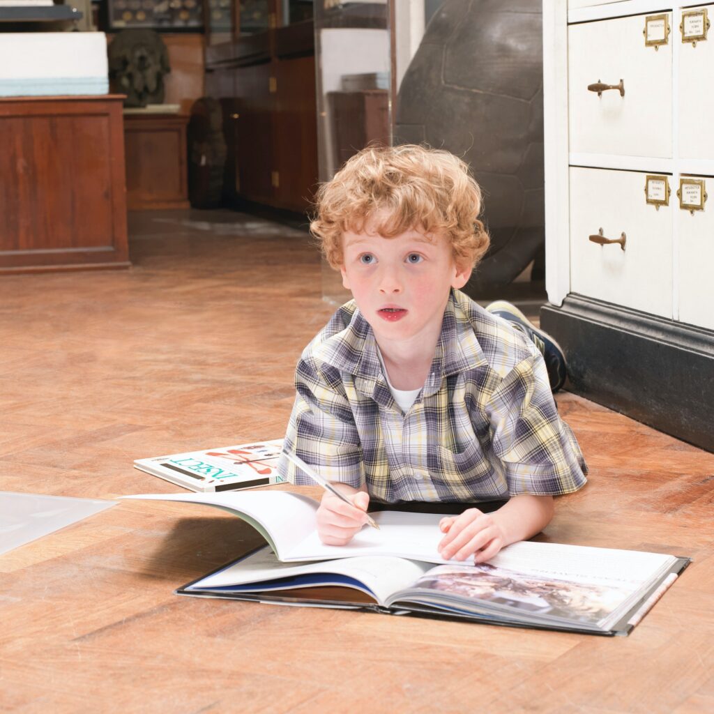 Boy looking up from book and note pad